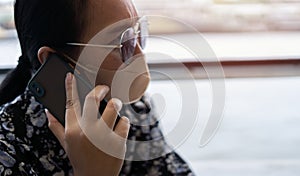 Middle-aged Asian woman looking worried and serious while talking on mobile phone in a port