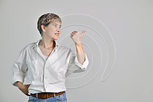 Middle aged Asian woman pointing fingers up at empty copy space for text isolated on white background