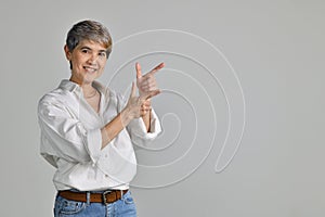 Middle aged Asian woman pointing fingers up at empty copy space for text isolated on white background