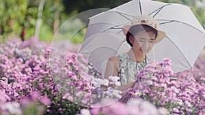 Middle aged asian woman using a tablet while checking the quality of flowers in garden