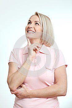 Middle-aged beautiful woman looking up thinking and dreaming on white background