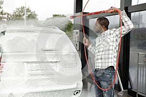 Middle aged black man cleaning his car outside in the car wash