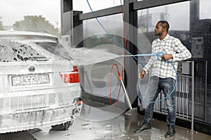 Middle aged black man cleaning his car outside in the car wash
