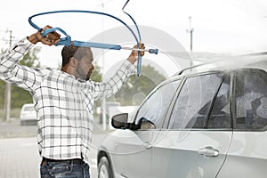 Middle aged black man cleaning his car outside in the car wash