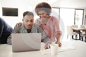 Middle aged African American  mum helping her teenage son do his homework using a laptop, close up