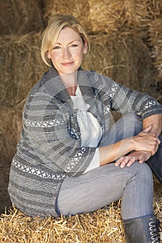 Middle Aged Blond Woman Sitting on Hay Bale