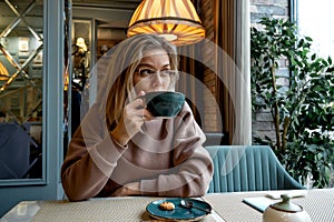 Middle-aged blonde caucasian woman drinks coffee in cafe
