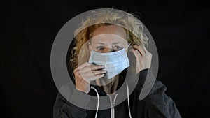 Middle-aged blonde woman demonstrates how to use the face mask to protect herself from the risk of contagion from covid-19