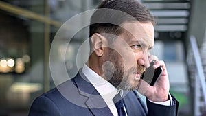 Middle aged boss talking on mobile, serious talk, confidence and determination