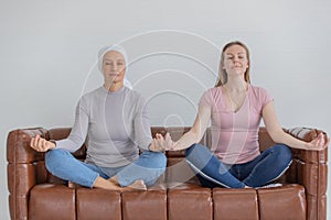 A middle-aged breast cancer woman with clothing around her head affected from chemotherapy and her daughter doing yoha together on