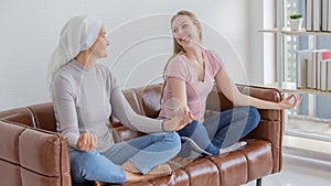 A middle-aged breast cancer woman with clothing around her head affected from chemotherapy and her daughter doing yoha together on