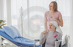 A middle-aged breast cancer woman with clothing around her head effected from chemo therapy sitting on wheel chair and hold hand