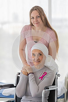 A middle-aged breast cancer woman with clothing around her head effected from chemo therapy sitting on wheel chair and hold hand