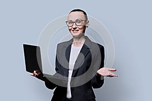 Middle-aged business confident woman using laptop on gray background