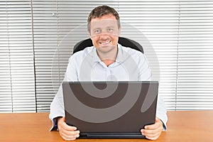 Middle aged business man working on laptop office desk