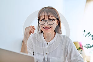 Middle aged business woman working at desk in home office, using laptop