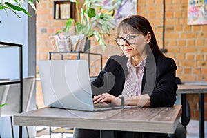 Middle-aged business woman working remotely with laptop in coworking