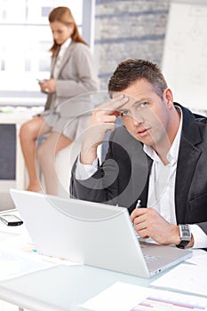 Middle-aged businessman sitting troubled at desk