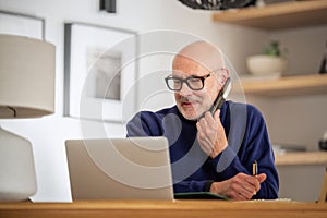 Middle aged businessman using smartphone and laptop while working from home