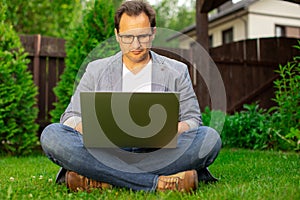 Middle aged businessman working on laptop outdoors, checking stock market