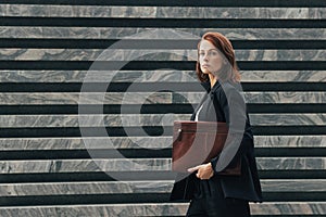 Middle-aged businesswoman in black formal clothes looking away while walking