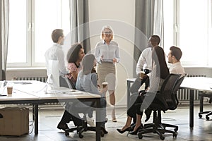 Middle aged businesswoman boss mentor training interns employees in office photo