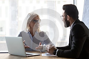 Middle-aged businesswoman discuss idea with male colleague at meeting