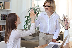 Middle aged businesswoman giving high five to her young female collegue photo