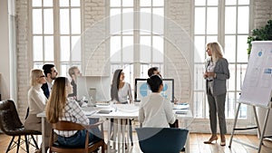 Middle-aged businesswoman lead meeting presenting project on whiteboard