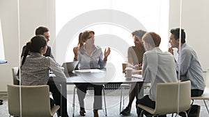 Middle-aged businesswoman speaking at diverse group negotiations at conference table