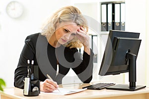 Middle-aged businesswoman working in office and examining reports