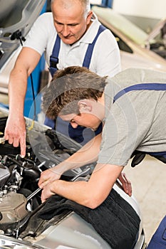 Middle aged car repairman helping colleague