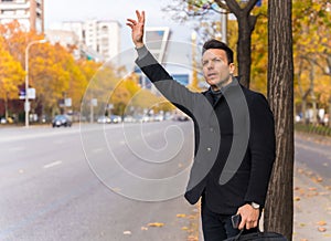 Middle-aged caucasian businessman hailing a taxi raising his hand to go to work