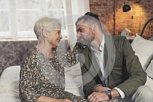 middle-aged caucasian businessman making silly faces and making his elderly grey-haired mother laugh