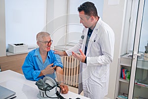 Middle aged caucasian doctor explains to his senior patient his blood pressure readings while standing next to him