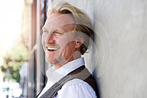 Middle aged caucasian man leaning to wall and laughing