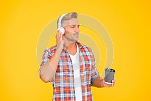 Middle-aged caucasian man listen to music in earphones holding hot coffee cup, break time