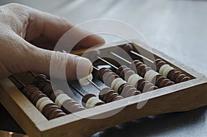 A middle-aged Caucasian man makes calculations on a wooden abacus
