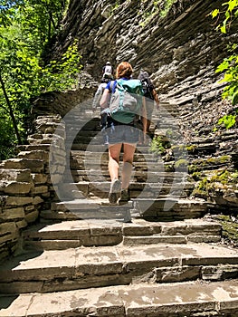 Middle aged Caucasian redheaded woman climbing stairs at Watkins Glen State Park, New York, United States