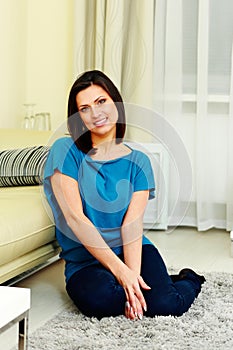 Middle-aged cheerful woman sitting on the floor