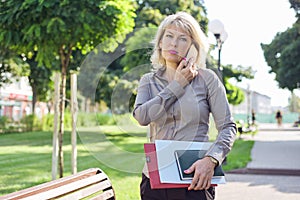 Middle-aged confident business woman talking on smartphone