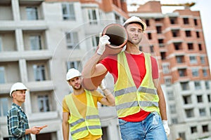 Middle-aged construction manager observing the work of young loaders