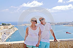 Middle-aged couple of baby boomers people posing for photograph opposite blue sea