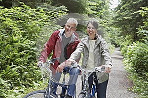 Middle Aged Couple With Bikes In Forest