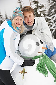 Middle Aged Couple Building Snowman On Ski Holiday