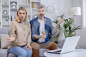 Middle-aged couple with concerns discussing finances at home