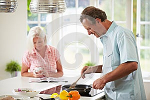 Middle Aged Couple Cooking Meal In Kitchen Together