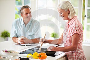 Middle Aged Couple Cooking Meal In Kitchen Together