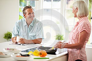 Middle Aged Couple Cooking Meal In Kitchen Together