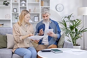 Middle-aged couple discussing financial documents at home in living room